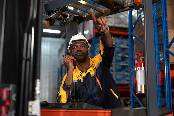 istock Black man driver forklift worker using walkie talkie while moving goods product to shelf at warehouse factory store. Logistics, Distribution Center concept 2219135817
