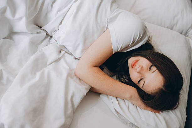 istock Teen girl sleeping peacefully in white bed sheets 2219141541