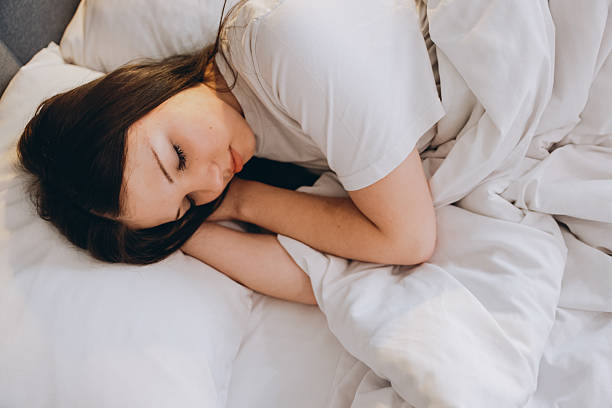 istock Teen girl sleeping peacefully in white bed sheets 2219141564