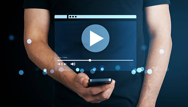 istock Man holding smartphone with virtual video player interface and play button on dark background showing online streaming technology concept. 2219143159