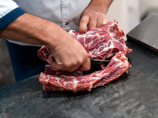 istock Butcher cutting raw meat with knife on cutting board 2219146637