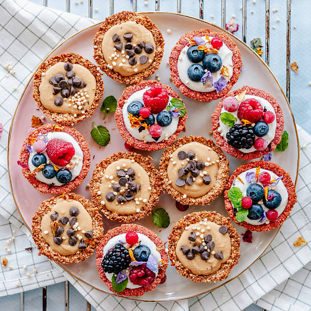 Overhead view of healthy homemade granola tartlets filled with yoghurt, peanut butter, berries and chocolate chips