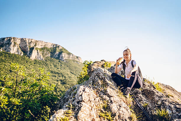 Happy young woman hiking in nature and drinking water.