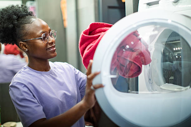 Young adult woman using washing and drying machine
