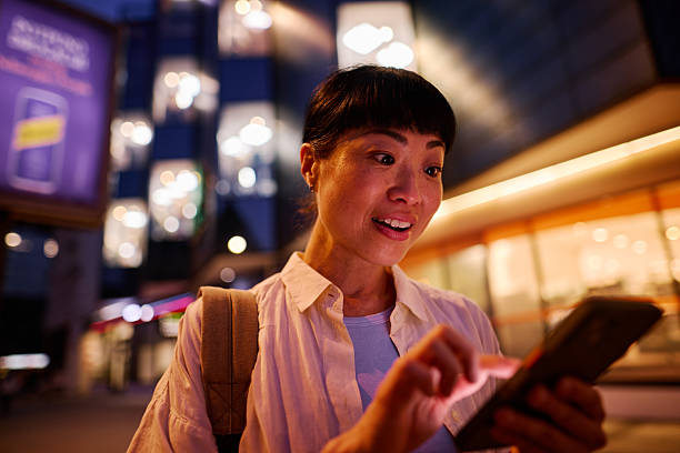 istock Smiling tourist using smartphone at night in city center 2219153064