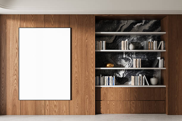 istock Modern interior with wooden wall paneling, empty vertical frame, and built-in bookshelf with marble texture and neatly arranged books and decor pieces. 3D Rendering 2219153391
