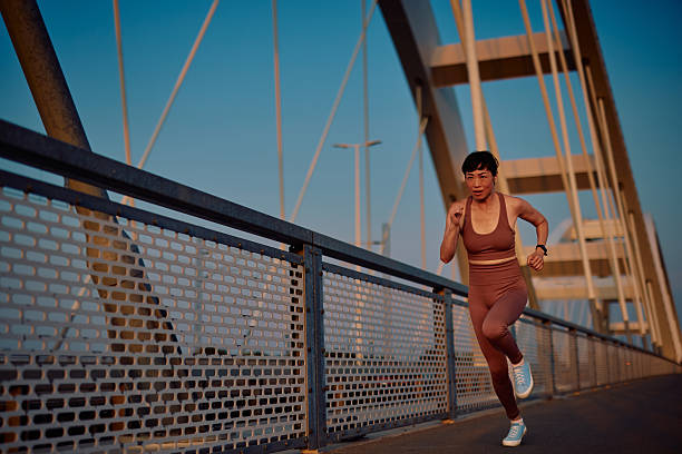 istock Determined mature asian woman running on a bridge at sunset 2219154831