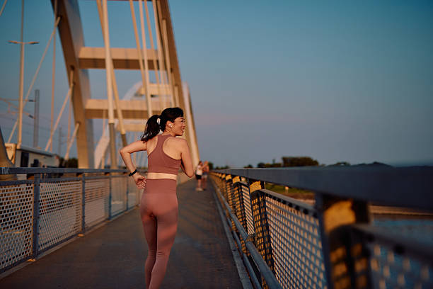 istock Young sportswoman running on the bridge at sunset 2219154862