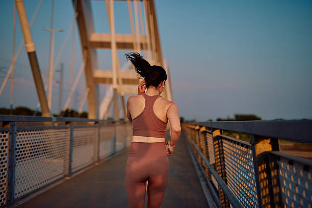 istock Young sportswoman running on a bridge at sunset 2219154865