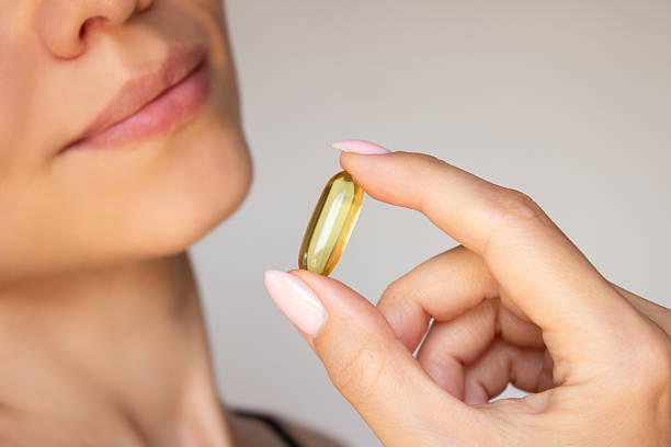 istock Young beautiful woman holding omega 3 capsule 2219158743