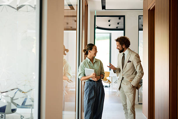istock Businesspeople talking and smiling in modern office hallway 2219159102