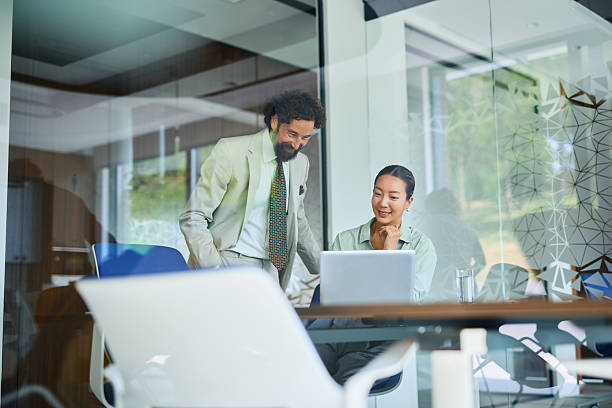 istock Smiling business people working together using laptop in modern office 2219159207