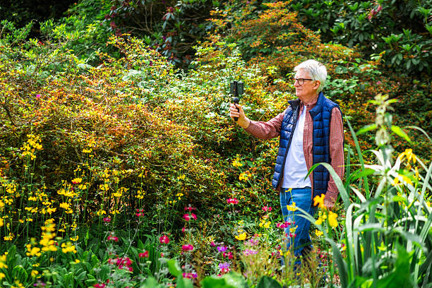 istock Senior man vlogging using smart phone in tranquil flower garden 2219160064