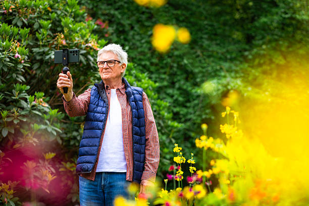 istock Senior man vlogging using smart phone in tranquil flower garden 2219160103