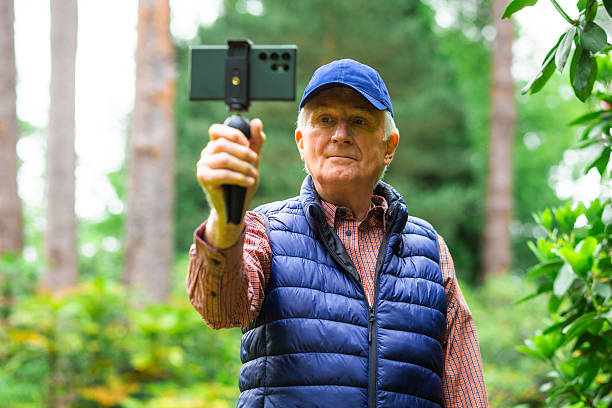 istock Senior man vlogging using smart phone in tranquil flower garden 2219160140