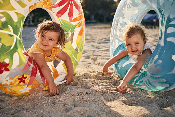 Beautiful twin sisters enjoying sunset on a beach vacation, playing with swimming floats..