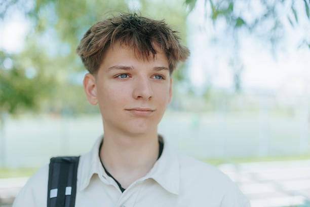 istock Teen walks with papers and backpack through quiet green schoolyard 2219164664