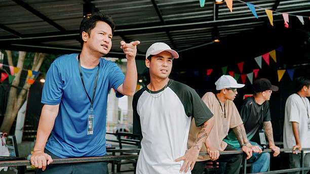 An Asian man pointing out the skateboard route to a young boy who participated in the competition.