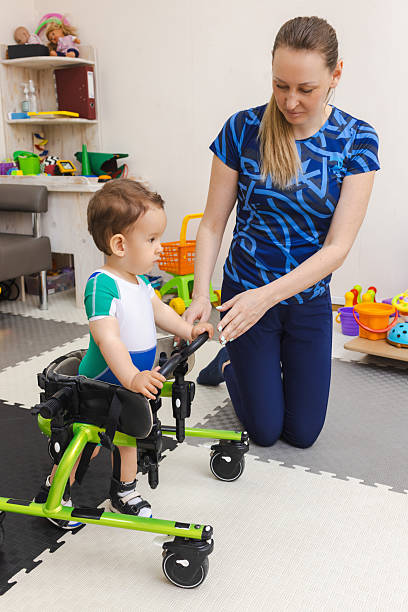 istock Handsome young boy with movement disorders practices walking with support from a therapist in rehabilitation clinic 2219170718
