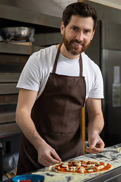 istock Man spreads sauce pizza in kitchen working neatly preparing meal 2219181920