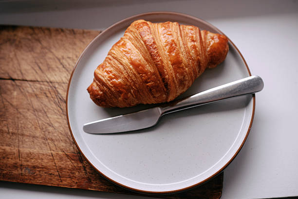 Single croissant on a plate from above. Hand made from an artisan bakers.
