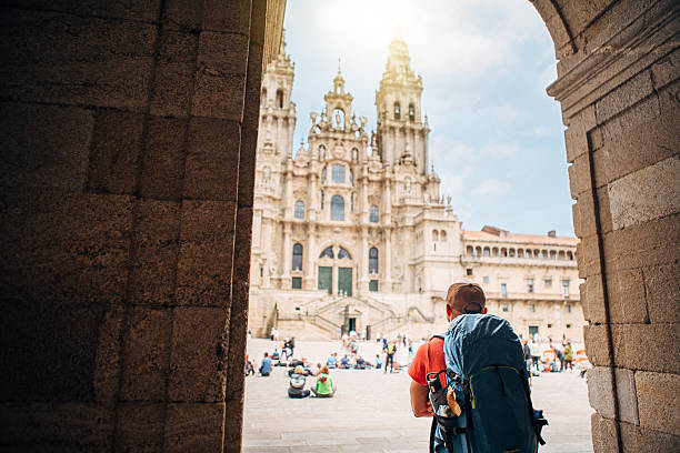 Middle-aged backpacker pilgrim on Obradoiro square in Santiago de Compostela, Spain, enjoying Santiago de Compostela Cathedral â famous Camino de Santiago finish point.
