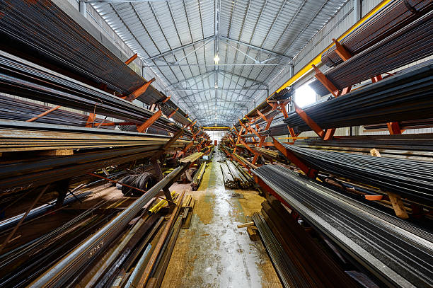 Aisle between racks with rolled metal products in non warming plant warehouse. Steel profile stored in manufacturing complex building