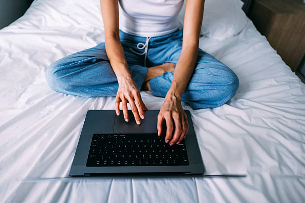 istock Woman in Comfortable Clothing Using Laptop While Sitting on Bed 2219204247