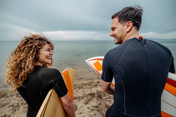 istock Rear view of young couple standing on a beach with surfboards 2219205421