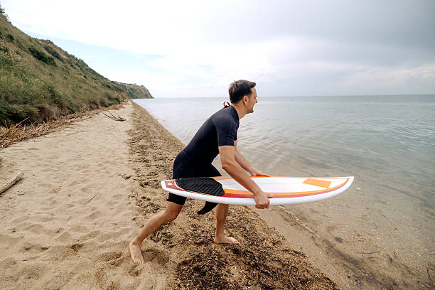 Side view of surfer getting ready go enter sea, going towards the water