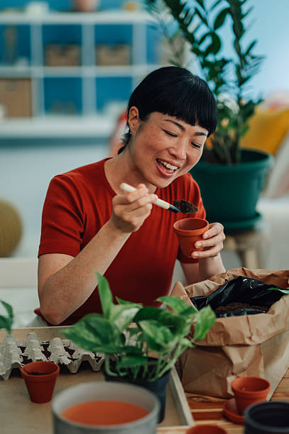 Woman repotting plants at home smiling and having fun