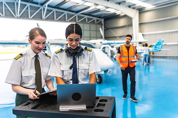 istock Female pilots using laptop in aircraft hangar 2219217245