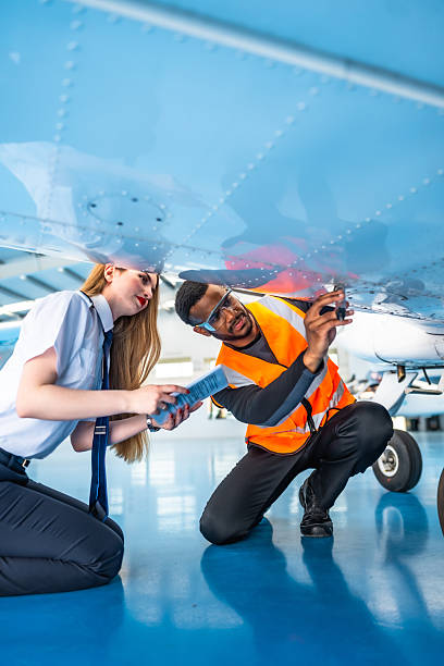 Aircraft maintenance engineer and pilot inspecting airplane in hangar