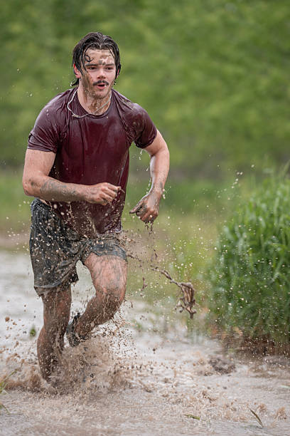 A determined individual participates in a challenging outdoor mud run, showcasing endurance, fitness, and perseverance in a natural setting.