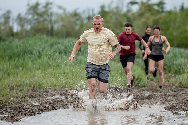 istock Group of People Running Through Mud During a Competitive Race 2219218494