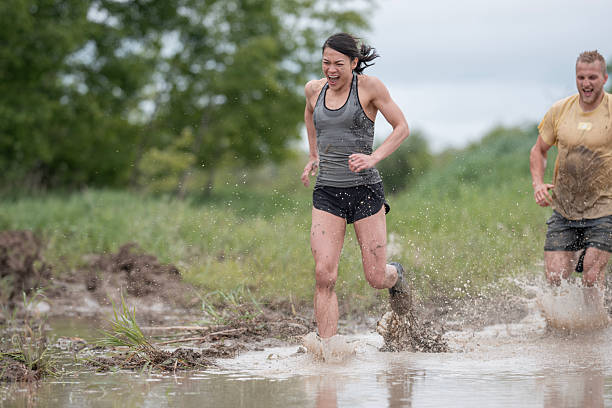 istock Group of Athletes Enjoying a Mud Run Through Wet and Challenging Terrain 2219219516