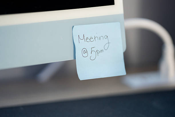 Sticky note on a computer monitor serves as a reminder for a scheduled 5 PM meeting.