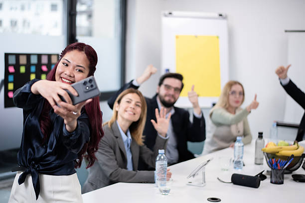 Group selfie in a modern office with coworkers celebrating success together