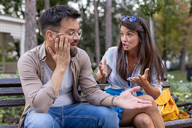 istock Man and woman engage in serious discussion on park bench 2219230544