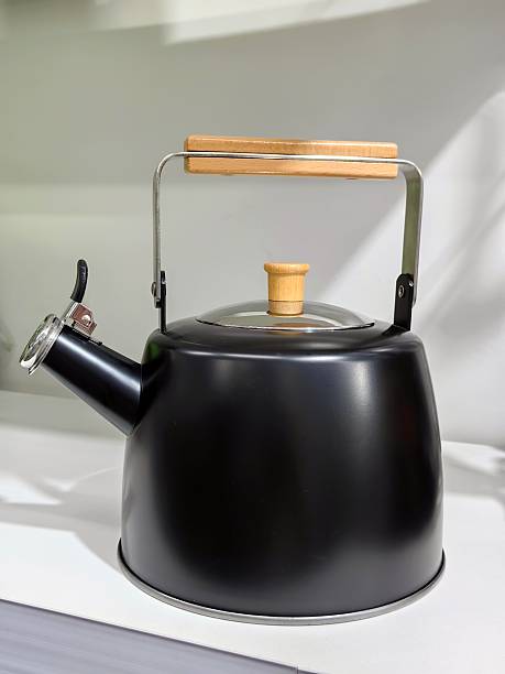 elegant black kettle with wooden handle in modern kitchen setting for tea and coffee preparation.