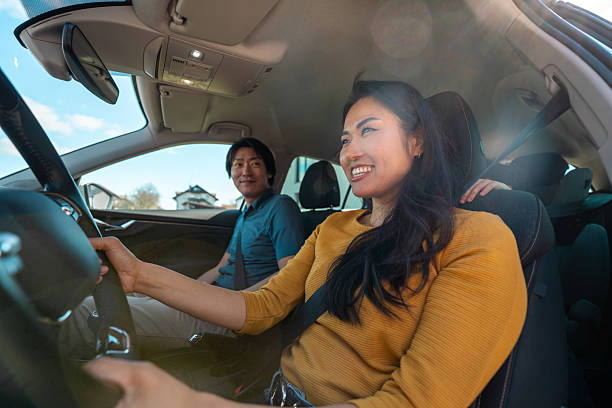 istock Smiling Asian Couple Enjoying a Sunny Road Trip Inside a Modern Car 2219242869