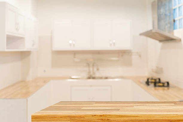 istock Empty wooden countertop table in modern white kitchen interior background with copy space for product display 2219245715