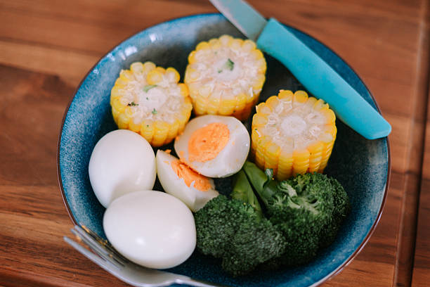 A colorful dish with boiled eggs, yellow corn, and green broccoli offers a healthy and nutritious choice for a meal.