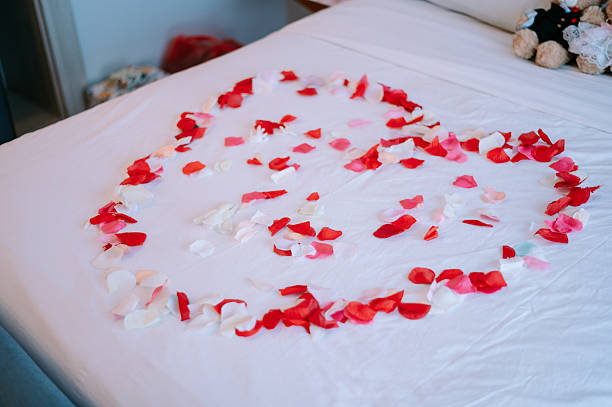 Beautiful romantic candles in a glass vases with flower petals on the floor