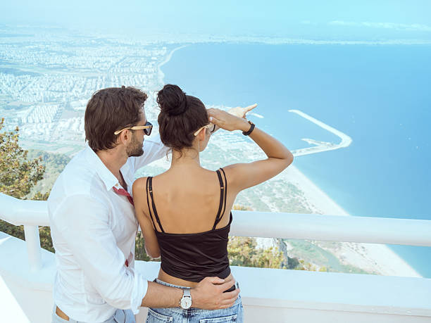 Stylish couple enjoying the panoramic view of Antalya s coast from Tunektepe Cable Car viewpoint. Perfect for travel, romance, vacation, and lifestyle promotional visuals.