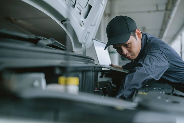 istock Man repairs a car engine with a laptop in a garage during daylight hours 2219251771