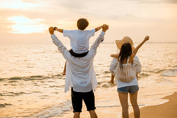 istock Parents carrying children on shoulders at the beach on sunset time 2219251955
