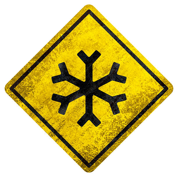 Yellow sign with black snowflake icon and worn texture, used for ice or winter weather warning.