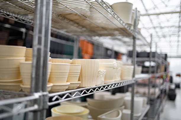 Flowerpots of various sizes are displayed on shelves in a garden center, ready for sale.