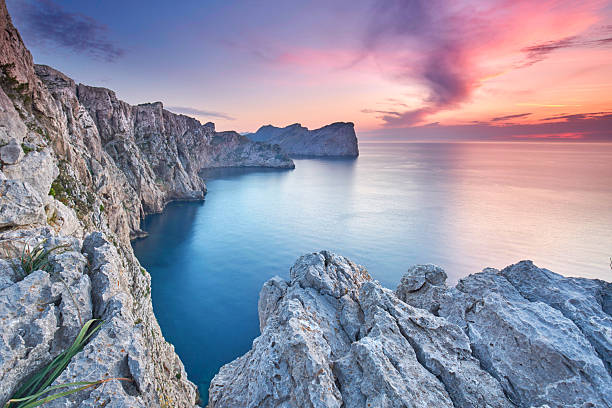 istock Tranquil Sunset Over Rugged Mediterranean Cliffs with Lush Green Bushes and a Serene Sea View 2219259123